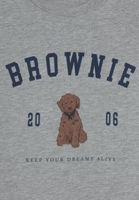 Camiseta de tela gris con texto en azul marino "BROWNIE" en la parte superior, un gráfico de un perro marrón en el centro y "MANTEN TU SUEÑO VIVO" debajo.
