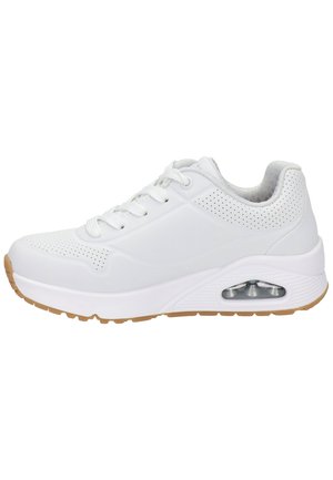 Baskets de sport blanches avec tige perforée, coussin d'air visible dans la semelle, lacets blancs et semelle en gomme sur un fond blanc.