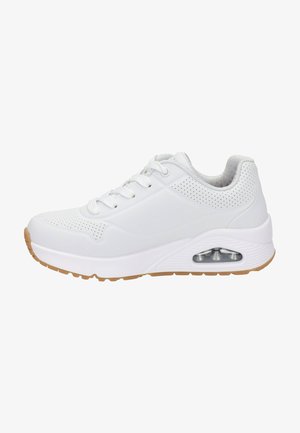 Witte sport sneaker met geperforeerde bovenkant, zichtbare luchtkussen in de zool, witte veters en een gumkleurige loopzool op een witte achtergrond.