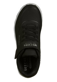 Sneaker nera con tomaia traspirante, dettagli testurizzati e una chiusura in velcro. Presenta una suola bianca e il marchio "Skechers" sul lato.