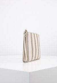 Pruhovaná kožená kabelka v krémové barvě, se svislými liniemi v béžové, námořnické modři a hnědé. Uzavírání na zip a hladká textura. Štíhlý a obdélníkový tvar.