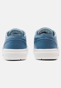 Sneakers in tela blu con design a profilo basso, suole in gomma bianca, colli imbottiti e dettagli di cucitura sottili sui lati.