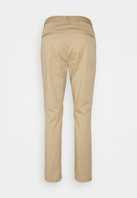 Pantalon beige à jambes droites avec passants pour ceinture et deux poches passepoilées à l'arrière, vu de dos sur un fond uni.