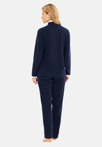 Navyblaues Fleece-Pyjama-Set mit langärmeligem Oberteil und Hose. Das Oberteil hat einen hohen Kragen, und die Bündchen sind mit weißen Akzenten versehen. Weiche Textur.