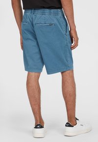 Blauwe shorts van zacht materiaal, met een elastische tailleband, zijzakken en twee achterzakken met een klein merkje.