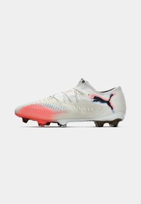 PUMA soccer cleat featuring a white fabric upper with pink accents, textured design, and black logo on the side; rubber studs for grip.
