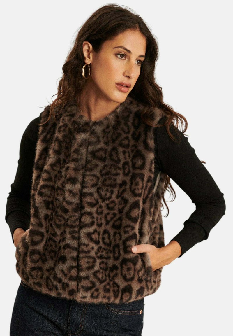 Faux fur luipaardprint gilet met een hoge hals, een ritssluiting aan de voorkant en zijzakken. Zwarte lange mouwen zijn zichtbaar eronder.