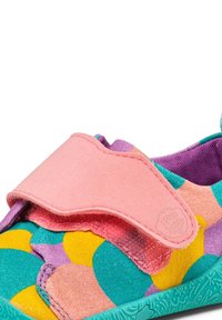 Zapato infantil colorido con una correa de Velcro rosa, patrones de lunares en turquesa, amarillo y púrpura, y con una suela verde texturizada.