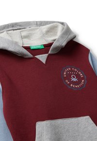 Bordeaux en grijze hoodie met een V-vormige halslijn, kangoeroezak en een circulair logo met "United Colors of Benetton" in het blauw.