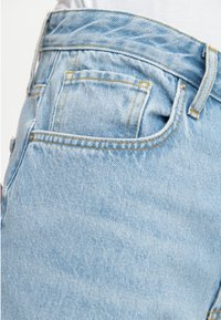 Jeans din denim de culoare albastru deschis, cu o croială clasică, cusături vizibile într-o nuanță galbenă contrastantă și un detaliu mic al unui buzunar pe spate.