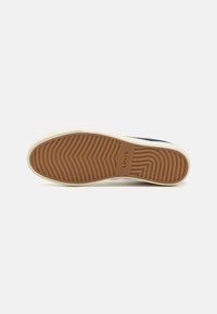 A Levi's sneaker talpa világosbarna gumiból készült. Hullámos futómintázattal rendelkezik, amelyen a márkajelzés is látható. Az élén textúra található, a oldalán pedig bézs kiemelés van.