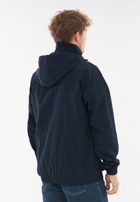Mørkeblå hættetrøje med en let, krøllet tekstur, der har elastiske manchetter og en snørerhætte. Set fra ryggen.