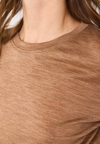 T-shirt marrone a maniche corte con scollo rotondo. Il tessuto appare morbido con una sottile texture e una leggera variazione di tonalità.