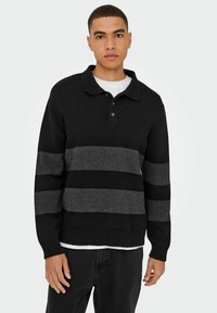 Schwarz- und grau gestreifter Pullover mit Kragen, drei Knöpfen und gerippten Bündchen und Saum. Das Material scheint gestrickt und strukturiert zu sein.