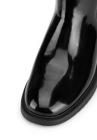 Cizme de gleznă din piele patent neagră cu un finisaj lucios, vârf rotunjit și talpă din cauciuc texturat. Suprafa�ță netedă fără modele vizibile.