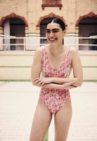 Pink floral swimsuit with a scoop neckline, featuring small flowers and strawberries. Smooth fabric, fitted style, and high-cut legs.