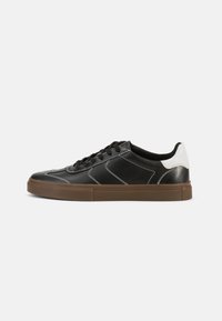 Sneaker in pelle nera con dettagli bianchi, con punta tonda, suola in gomma e cuciture a contrasto. Design minimalista con silhouette elegante.