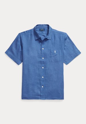 Kort blauw overhemd met knopen, borstzak met klein wit geborduurd logo, kraag en zichtbare witte knopen aan de voorkant.