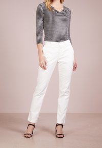 Zwart-wit gestreepte lange mouw top, gecombineerd met witte rechte broek en zwarte sleehakken. Soepele textuur, aansluitend ontwerp.
