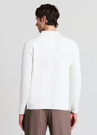 Weißer Pullover mit langen Ärmeln, Rundhalsausschnitt, glatter Textur und lockerer Passform, kombiniert mit braunen Hosen.