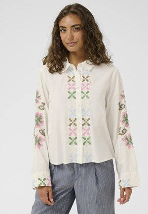 Hvid skjorte med knaplukning og blomstermønster i pink, blå, grøn og brun. Lange ærmer. Blødt, let stof med en afslappet pasform.