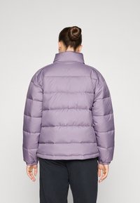 Lilla pufferjakke med høy krage, quiltede seksjoner og elastiske mansjetter. Slett, blankt stoff med en avslappet passform.