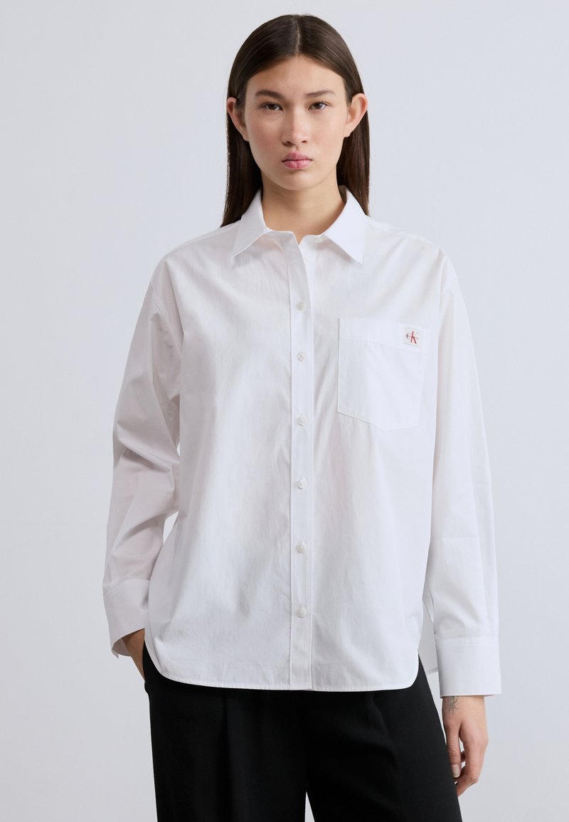 Λευκό πουκάμισο από βαμβάκι, με γιακά, μακριά μανίκια και τσέπη αριστερά στο στήθος με μικρό λογότυπο CK.