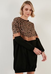 Schwarzes und beiges Kleid mit einem Oberteil im Leopardenprint, runder Ausschnitt und langen Ärmeln, akzentuiert durch einen gerafften Saum.