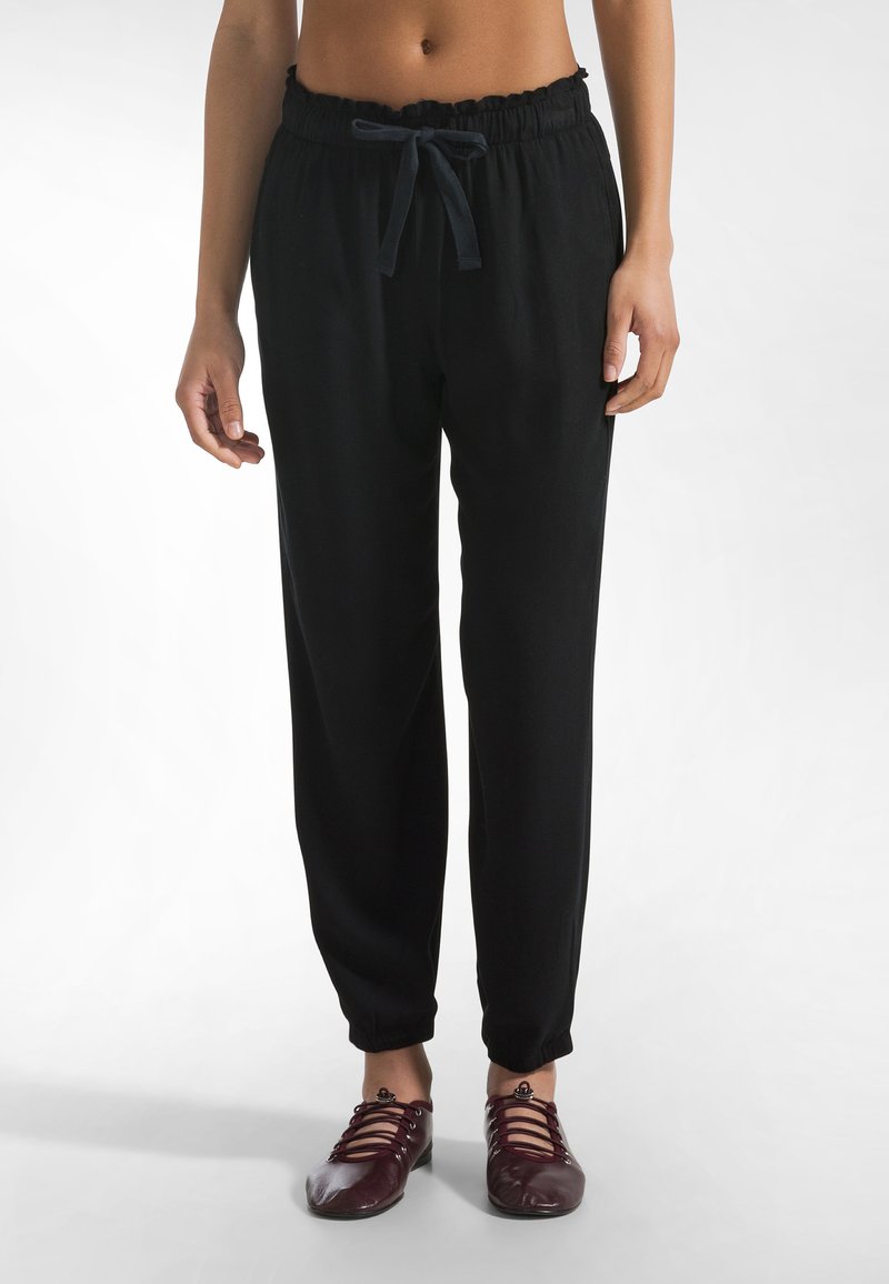 Pantalones negros de corte holgado con cintura elástica y cordón ajustable. Puños en los tobillos estrechos, fabricados con una tela suave.