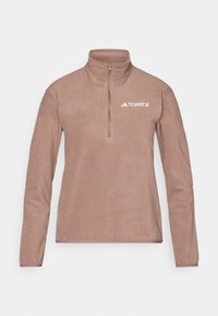 Sudadera de forro polar marrón con cuello de media cremallera, mangas largas y un pequeño logo blanco "TERREX" en el pecho izquierdo. Textura suave, diseño minimalista.