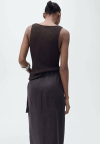 Braun geripptes Tanktop kombiniert mit einem grauen, fließenden Rock. Einfaches Design mit einem figurbetonten Oberteil und einem lockeren, langen Rock, der bis zum Boden reicht.