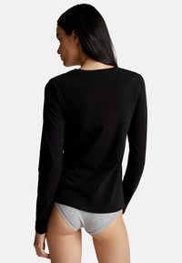 Czarna koszula z długim rękawem, wykonana z gładkiego materiału, z prostym okrągłym dekoltem i dopasowanym krojem. Noszona z szarym bielizną.