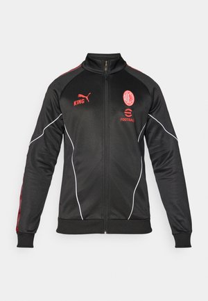 Juodas sportinis švarkas su raudonomis detalėmis, užtrauktuko uždarymas, aukštas apykaklė, Puma logotipas ir komandos emblema. Yra tekstūruotas audinys ir balti apvadukai.