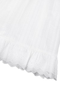 Tissu blanc avec des rayures verticales texturées et un volant festonné en dentelle ajourée en bas.