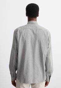 Camicia a pulsante a quadri in bianco e nero, con colletto standard, maniche lunghe e una vestibilità comoda. Tessuto testurizzato con un motivo visibile.