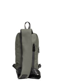 Zielony plecak ze splotu nylonowego o teksturowanym wykończeniu, z regulowanym paskiem, górnym uchwytem i boczną kieszenią na zamek do przechowywania.