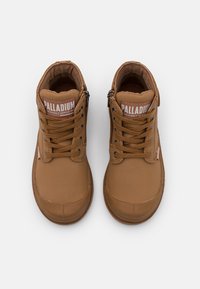 Hnědé vysoké sneakers s hladkým, koženým materiálem. Obsahují zavazování na šněrování vpředu, postranný zip a značku "PALLADIUM" na jazyku.