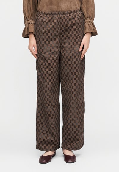 Brune vide bukser med bred ben og et geometrisk svart mønster, med elastisk midje. Kombinert med burgunder flate sko.