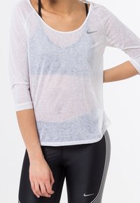 White, lightweight, long-sleeve shirt with a scoop neck and semi-sheer fabric, featuring a small gray Nike logo on the chest.