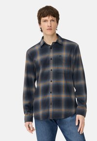 Chemise boutonnée en carreaux bleu foncé et gris, avec des accents à carreaux orange, une poche poitrine et des manches longues avec poignets à boutons.