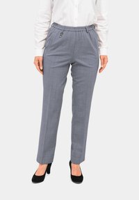 Grijze op maat gemaakte broek van een gestructureerde stof, met een elastische tailleband en een sluitingdetail, gecombineerd met zwarte hoge hakken.