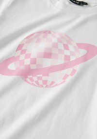 Camiseta blanca con un diseño de planeta de tablero de ajedrez rosa con anillos, textura suave y mangas cortas.