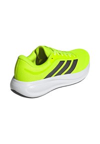 Hellgelb-grüner Laufschuh mit schwarzen Streifen, weißer gedämpfter Sohle und Mesh-Obermaterial, schräg gestellt, um Seiten- und Rückendetails zu zeigen.