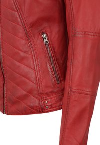 Rote Lederjacke mit gesteppten Mustern, einer Reißverschlusstasche und Metallbeschlägen. Glatte Textur mit passgenauen Designelementen.