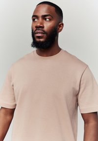Short-sleeve, crew-neck t-shirt in light beige, made of smooth fabric with a slightly relaxed fit and sturdy stitching, no patterns or graphics.
