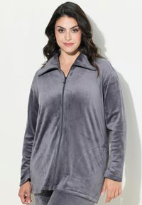 Giacca in pile grigia, con zip, colletto alto, tasche laterali, maniche lunghe e una finitura morbida e texturizzata.