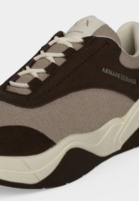Baskets beige et marron foncé Armani Exchange avec lacets blancs et semelle épaisse blanche et noire, vues de côté.