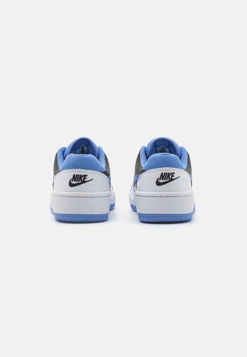 Baskets Nike avec une base en cuir blanc, des accents bleus, des panneaux gris et des capuchons de talon bleus texturés. Logo noir à l'arrière.