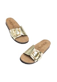 Gold metallic slide sandals with a wide strap and a decorative buckle. Soft tan footbed with black rubber sole. Flat design.