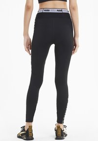 Czarne legginsy z wysokim stanem, z odblaskowym logo PUMA, wykonane z elastycznego materiału z bocznymi detalami.